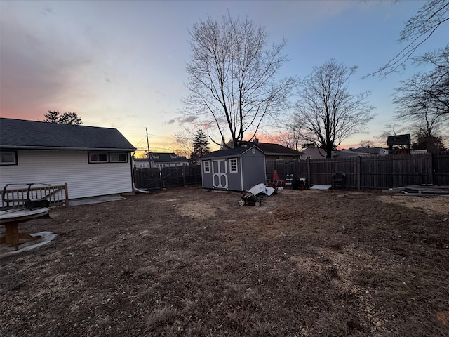 view of yard with a fenced backyard, an outdoor structure, and a storage shed