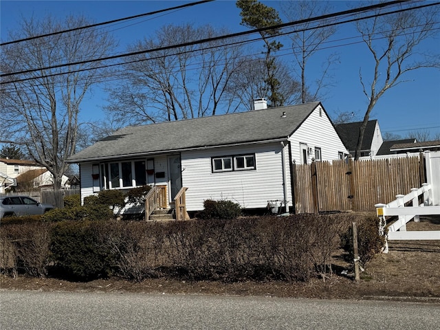 view of front of property featuring roof with shingles, fence, and a chimney