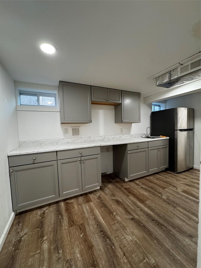 kitchen with baseboards, dark wood finished floors, gray cabinets, freestanding refrigerator, and a sink