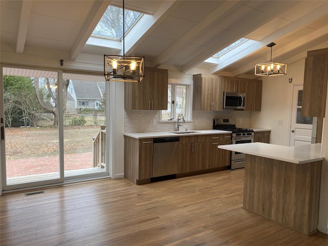 kitchen featuring brown cabinetry, appliances with stainless steel finishes, light countertops, and a sink