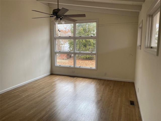 empty room featuring visible vents, lofted ceiling with beams, ceiling fan, wood finished floors, and baseboards