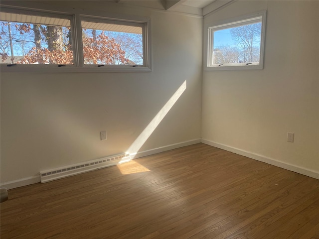 unfurnished room with baseboards, baseboard heating, and wood finished floors