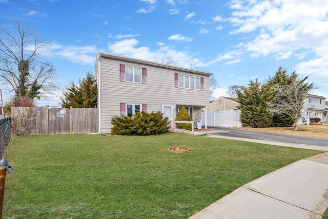 view of front of home featuring driveway, fence, and a front yard