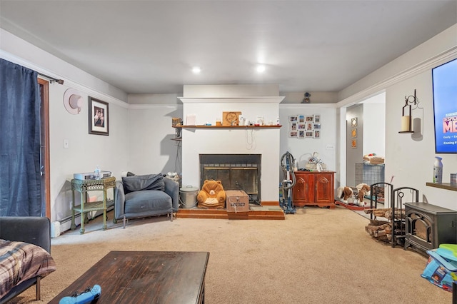 living area featuring a wood stove, carpet, a fireplace with raised hearth, and a baseboard radiator