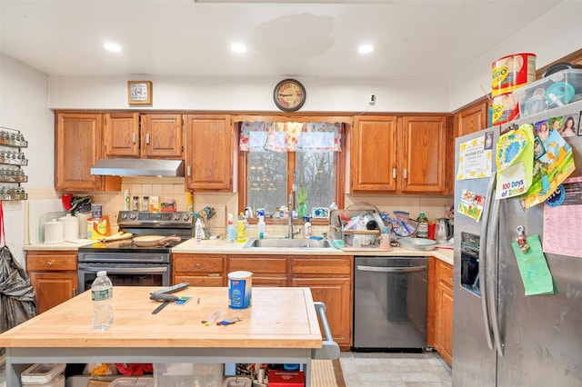 kitchen with stainless steel appliances, light countertops, decorative backsplash, a sink, and extractor fan