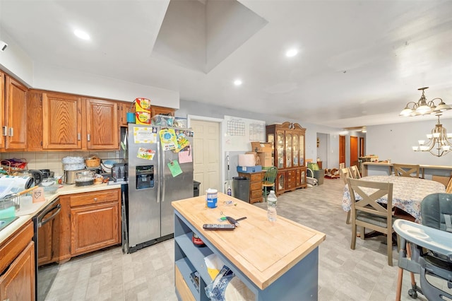 kitchen featuring light floors, stainless steel fridge, a chandelier, and brown cabinets