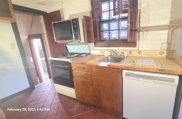 kitchen featuring a sink, range with gas stovetop, dishwasher, tasteful backsplash, and stainless steel microwave