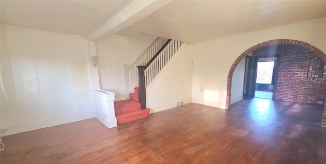 unfurnished room featuring stairs, arched walkways, wood finished floors, and ornamental molding