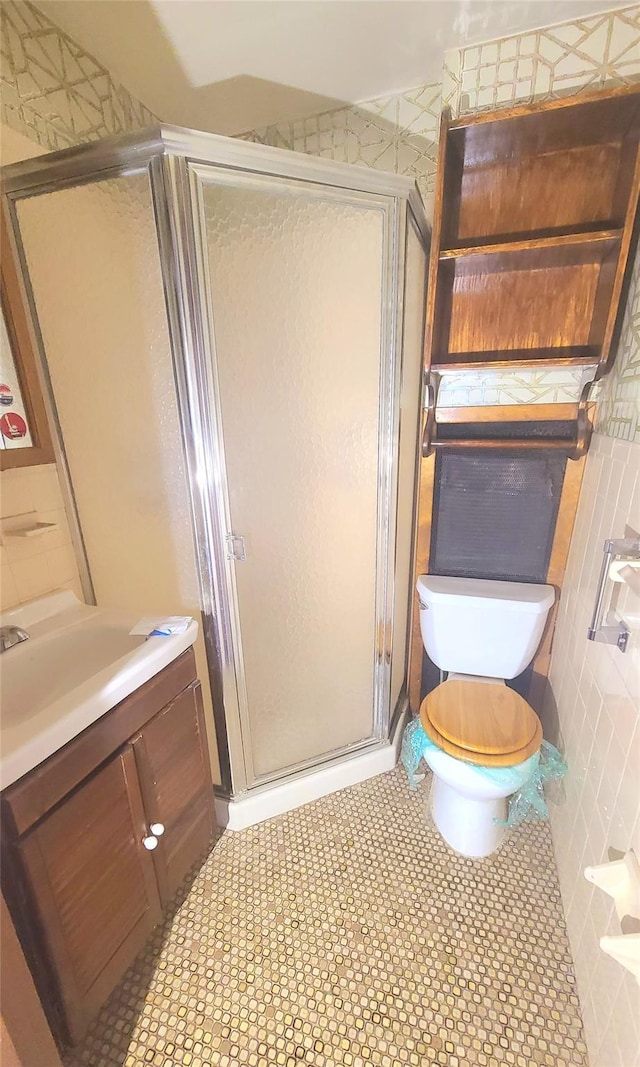 bathroom featuring toilet, a stall shower, and vanity