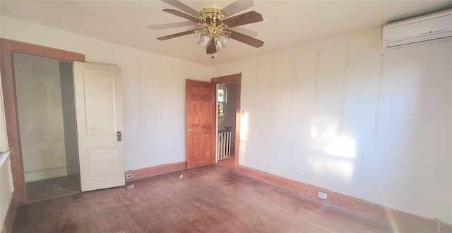 unfurnished bedroom featuring a wall unit AC, ceiling fan, baseboards, and wood finished floors