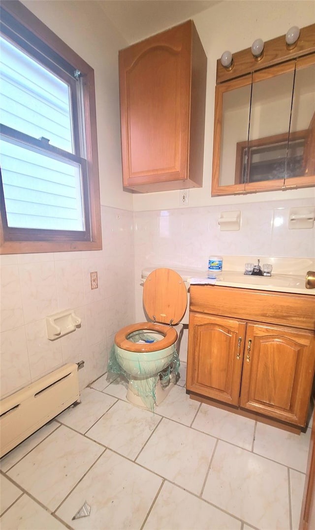 bathroom featuring a baseboard radiator, tile patterned flooring, toilet, vanity, and tile walls