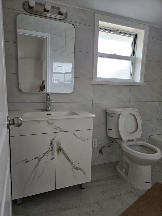 bathroom with toilet, tile walls, and vanity