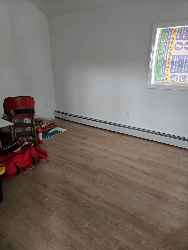 empty room with baseboard heating and wood finished floors