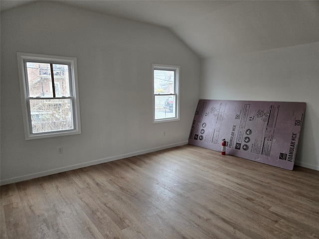 additional living space with a healthy amount of sunlight, vaulted ceiling, and wood finished floors