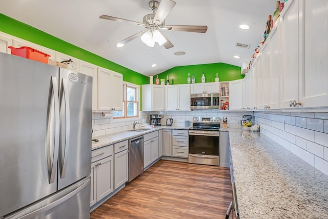 kitchen featuring wood finished floors, a sink, visible vents, vaulted ceiling, and appliances with stainless steel finishes