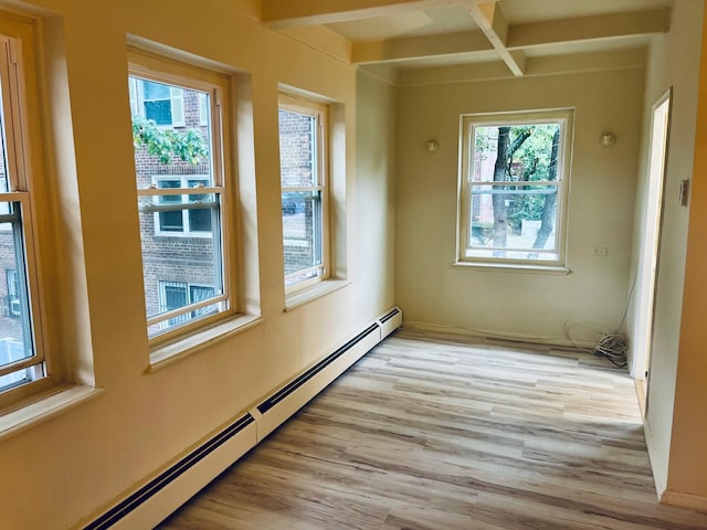 empty room with light wood-type flooring, a baseboard radiator, and beam ceiling