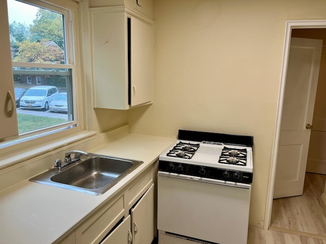 kitchen with a wealth of natural light, white cabinets, a sink, and white gas stove