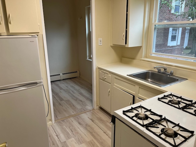 kitchen with white appliances, a sink, light wood-style floors, light countertops, and baseboard heating