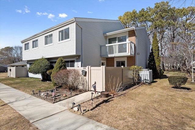 view of front of house with a front yard, brick siding, fence, and central AC unit