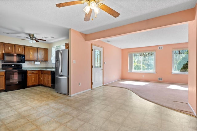 kitchen with light floors, open floor plan, light countertops, brown cabinets, and black appliances