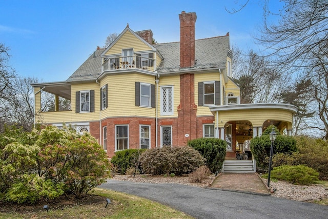 victorian house featuring a balcony and a chimney