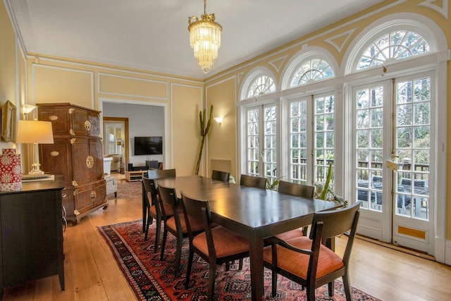 dining space featuring a chandelier, a decorative wall, and light wood finished floors