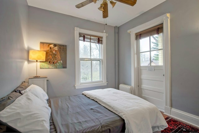 bedroom featuring baseboards, wood finished floors, radiator, and ceiling fan