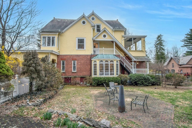 back of house with a patio, fence, stairway, and brick siding