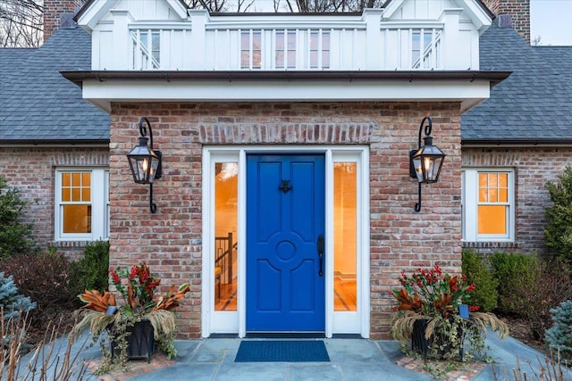 property entrance with brick siding, board and batten siding, a chimney, and a shingled roof