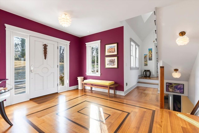 foyer featuring baseboards, light wood-type flooring, and a healthy amount of sunlight