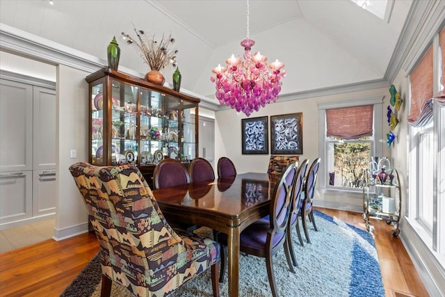 dining area featuring light wood-type flooring, an inviting chandelier, ornamental molding, and a wealth of natural light