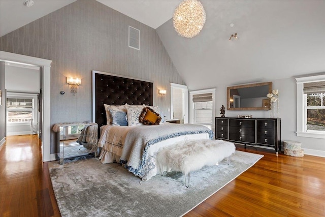 bedroom featuring wallpapered walls, baseboards, visible vents, wood finished floors, and high vaulted ceiling