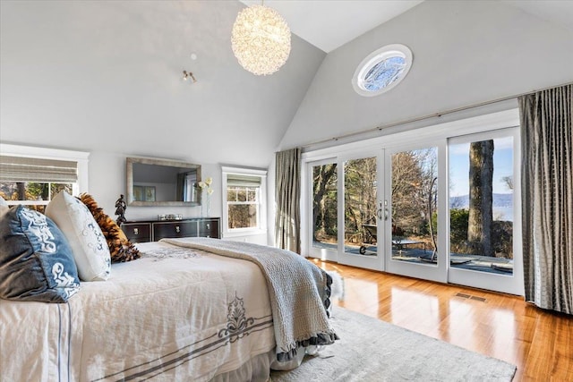 bedroom featuring visible vents, wood finished floors, an inviting chandelier, access to outside, and high vaulted ceiling