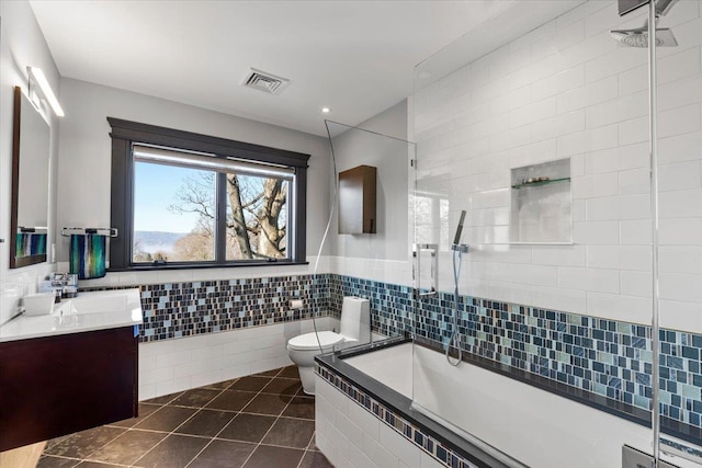 bathroom with tile patterned flooring, toilet, vanity, visible vents, and tile walls