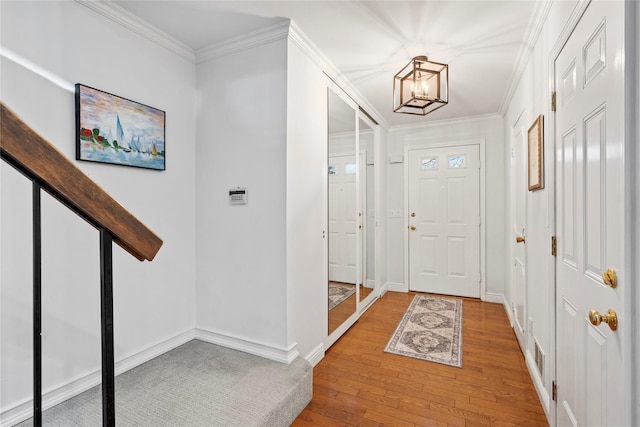 entryway featuring light wood-style flooring, baseboards, a chandelier, and crown molding