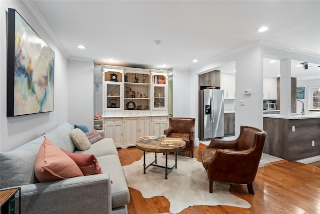 living room featuring ornamental molding, light wood-type flooring, and recessed lighting