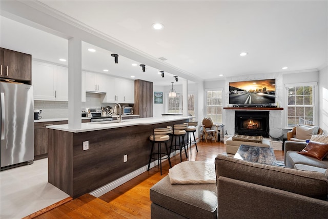 kitchen featuring a breakfast bar area, open floor plan, light countertops, stainless steel appliances, and a sink