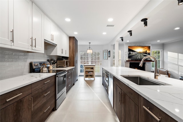 kitchen with backsplash, appliances with stainless steel finishes, white cabinetry, a sink, and dark brown cabinets