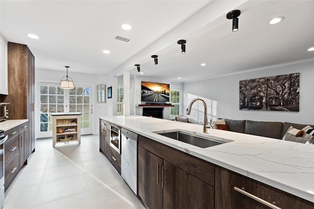 kitchen featuring recessed lighting, stainless steel appliances, a sink, open floor plan, and dark brown cabinets