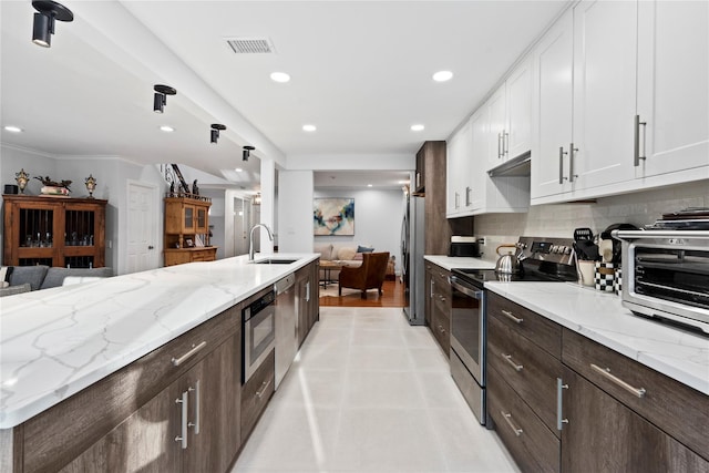 kitchen with visible vents, decorative backsplash, white cabinets, appliances with stainless steel finishes, and a sink