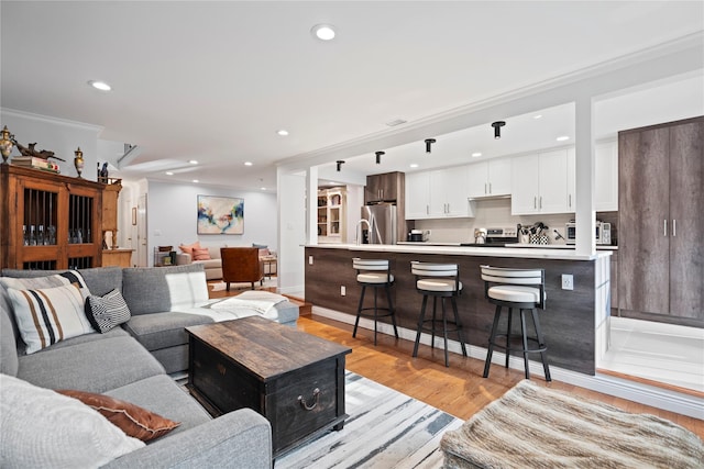 living area with baseboards, light wood finished floors, recessed lighting, and crown molding