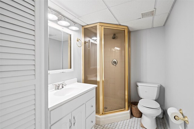 full bath featuring toilet, a shower stall, vanity, a drop ceiling, and tile patterned floors