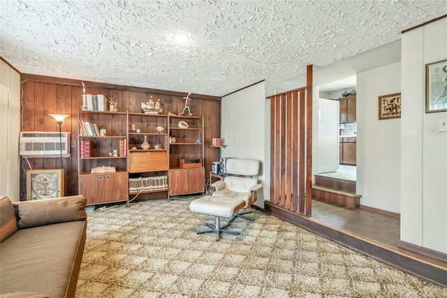 sitting room featuring a wall mounted air conditioner, wood walls, and a textured ceiling