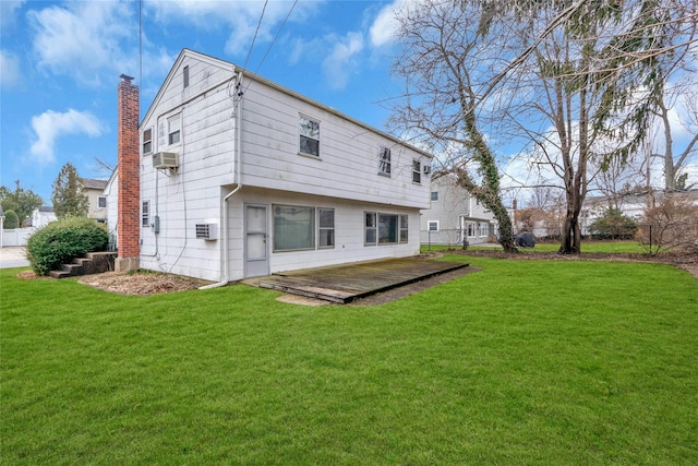 rear view of house with a wall unit AC, a yard, a wooden deck, and a chimney