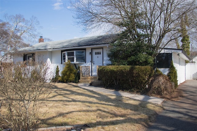 ranch-style home with a front lawn and a chimney