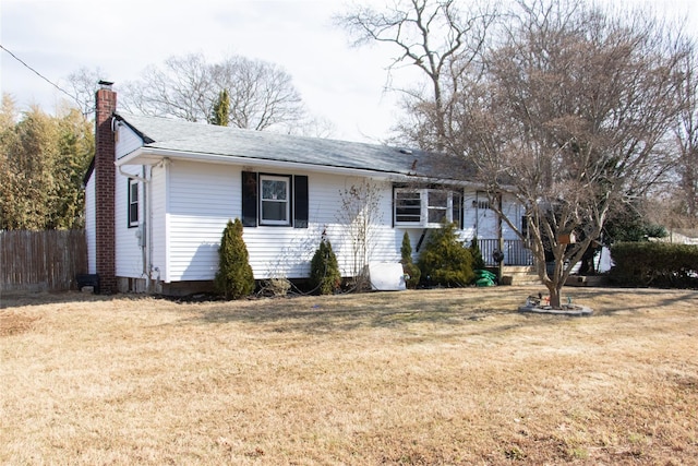 ranch-style house featuring a chimney, fence, and a front yard