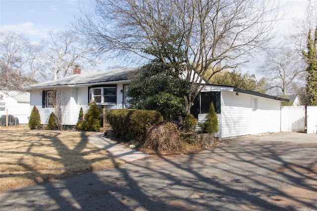 ranch-style house featuring a chimney, fence, and driveway