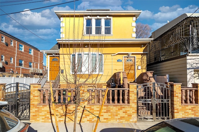 view of front facade featuring a fenced front yard, a gate, board and batten siding, and stucco siding