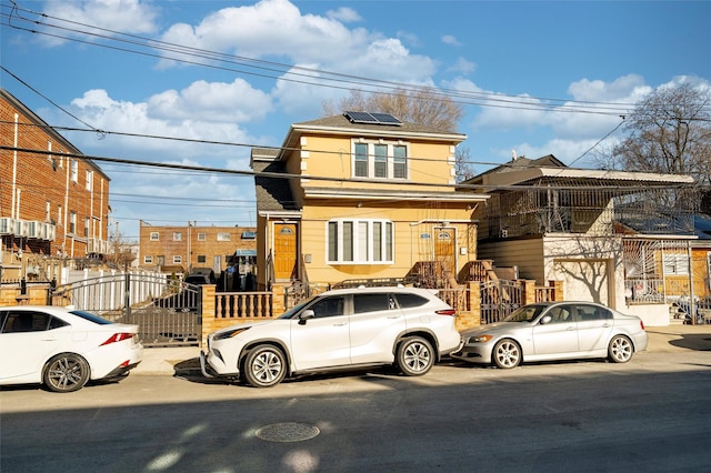 view of front facade with roof mounted solar panels and fence