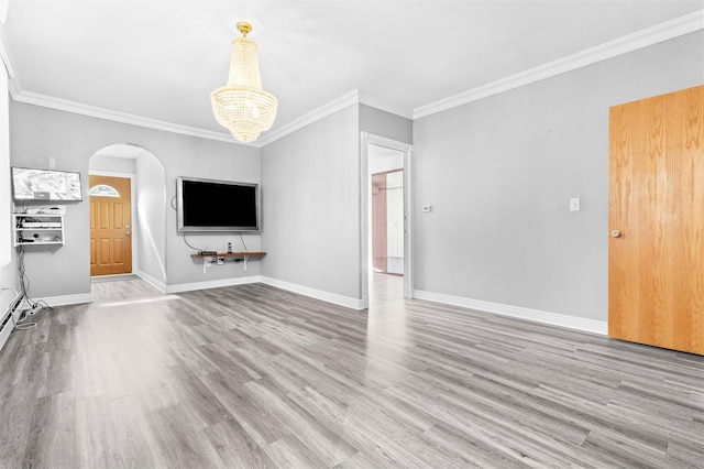 unfurnished living room with arched walkways, crown molding, an inviting chandelier, wood finished floors, and baseboards